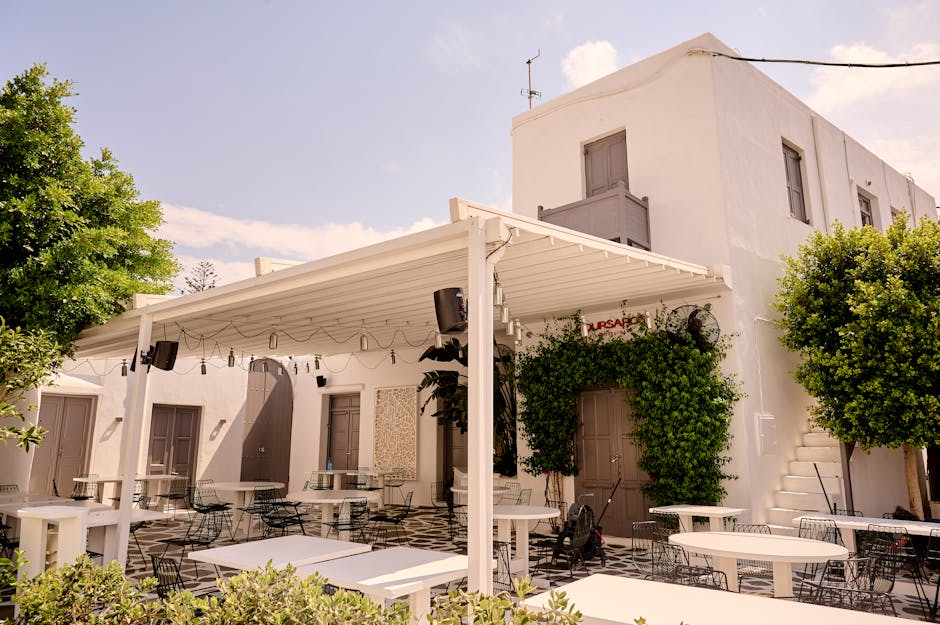 Idyllic outdoor patio with white architecture and lush greenery at a Mediterranean restaurant.